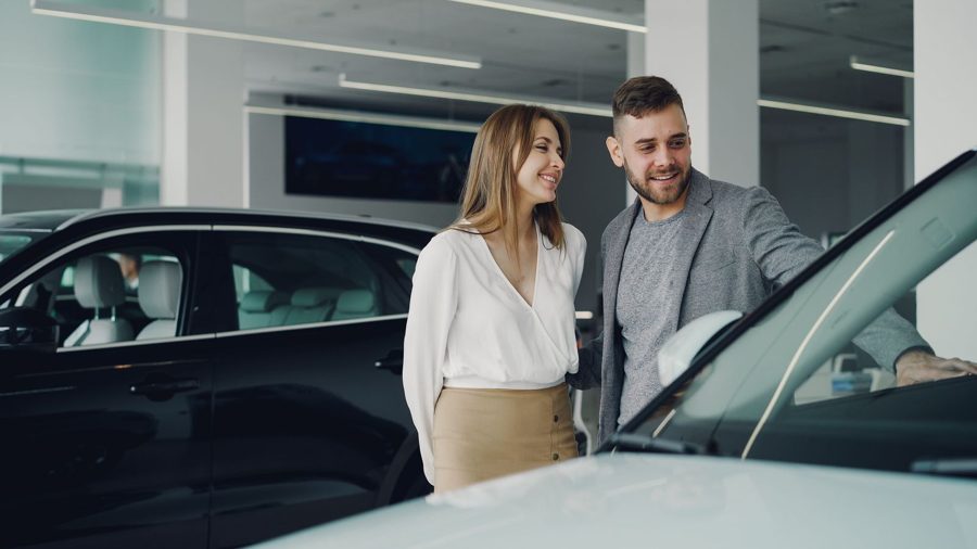 A couple looking over a car with a salesperson in a bright showroom