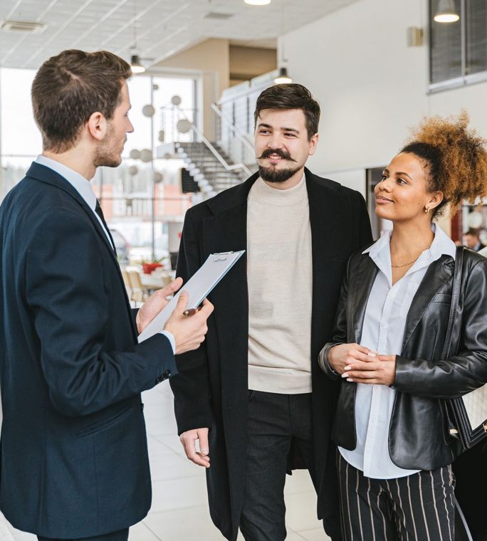 A salesperson talking through a vehicle with a couple in a showroom